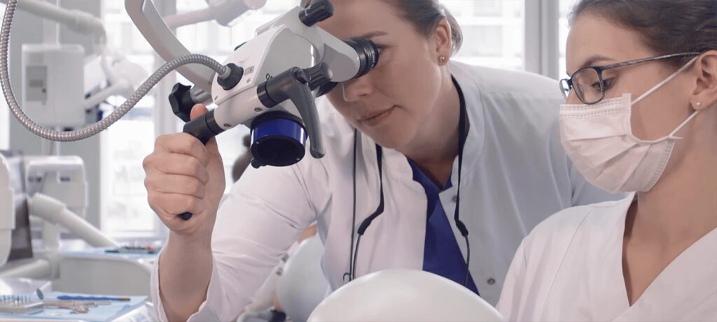 Dozent erklärt einer Studentin im Dental Skills Lab die Arbeit mit einem Dentalmikroskop.