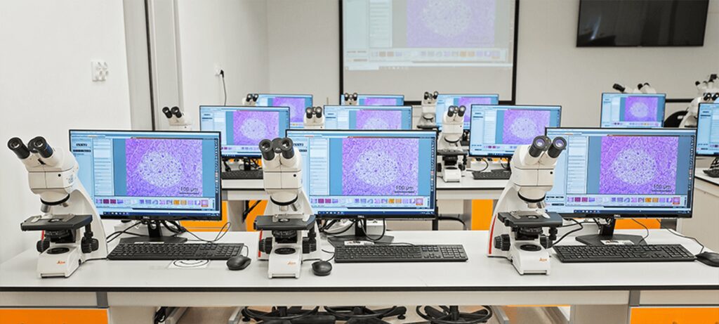 Mikroskopie-Schulungsraum mit Mikroskopen und synchronisierten Monitoren, gesteuert durch das Alphadidact-System.