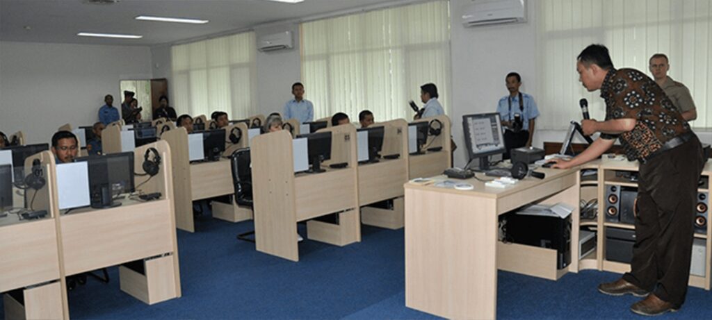 Militärischer Computer-Schulungsraum mit Teilnehmern an PCs und Dozent am Dozenten-Rechner.