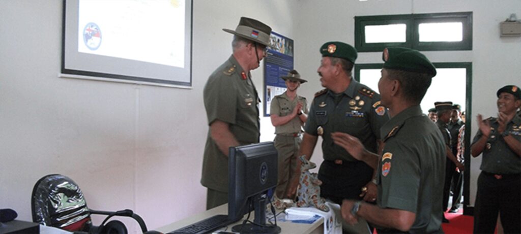 Militärischer IT-Schulungsraum mit Personen vor dem Dozenten, die auf eine Leinwand schauen.