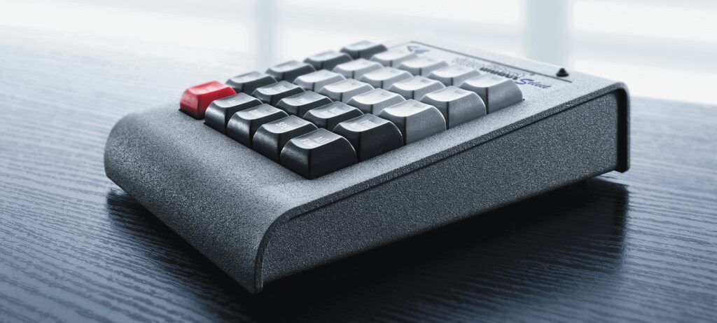 Systemsteuerungstastatur des Alphadidact-Systems auf einer dunklen Tischoberfläche.