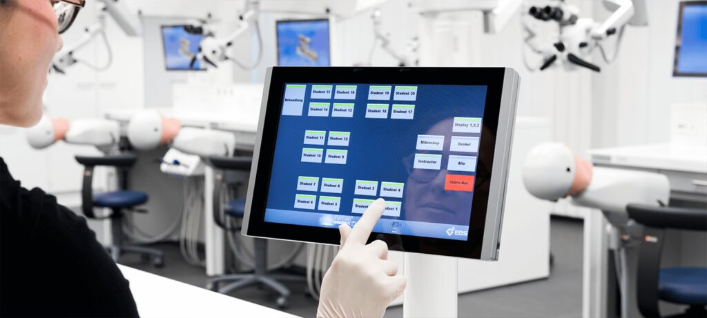 Eine Person bedient das Touchscreen des Alphadidact-Systems in einem modernen Schulungslabor.